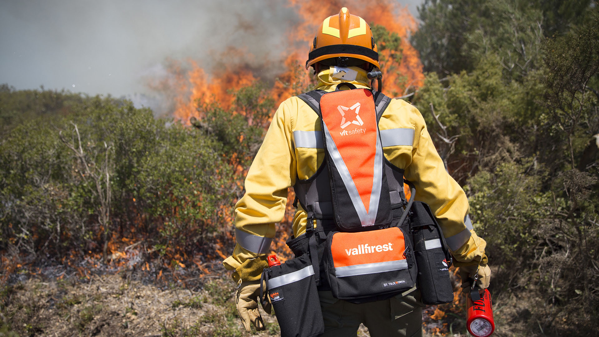 <span>Foto de bomber apagant foc per presentar el sistema d'identitat i arquitectura de marca de l'empresa d'equips professionals per a incendis forestals VALLFIREST. Aplicada en motxilla casc i material. Dissenyat per l'estudi esiete de branding i comunicaci&oacute; de Barcelona.</span>