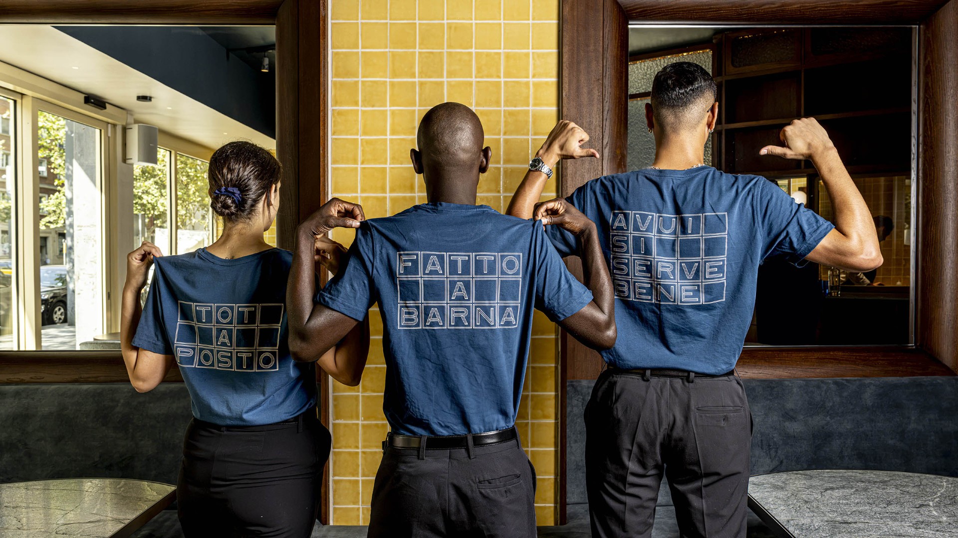 Tres miembros del equipo del restaurante Osteria Condal, en Barcelona, muestran camisetas azules con los lemas &laquo;Tot a posto&raquo;, &laquo;Fatto a Barna&raquo; y &laquo;Avui si serve bene&raquo;.