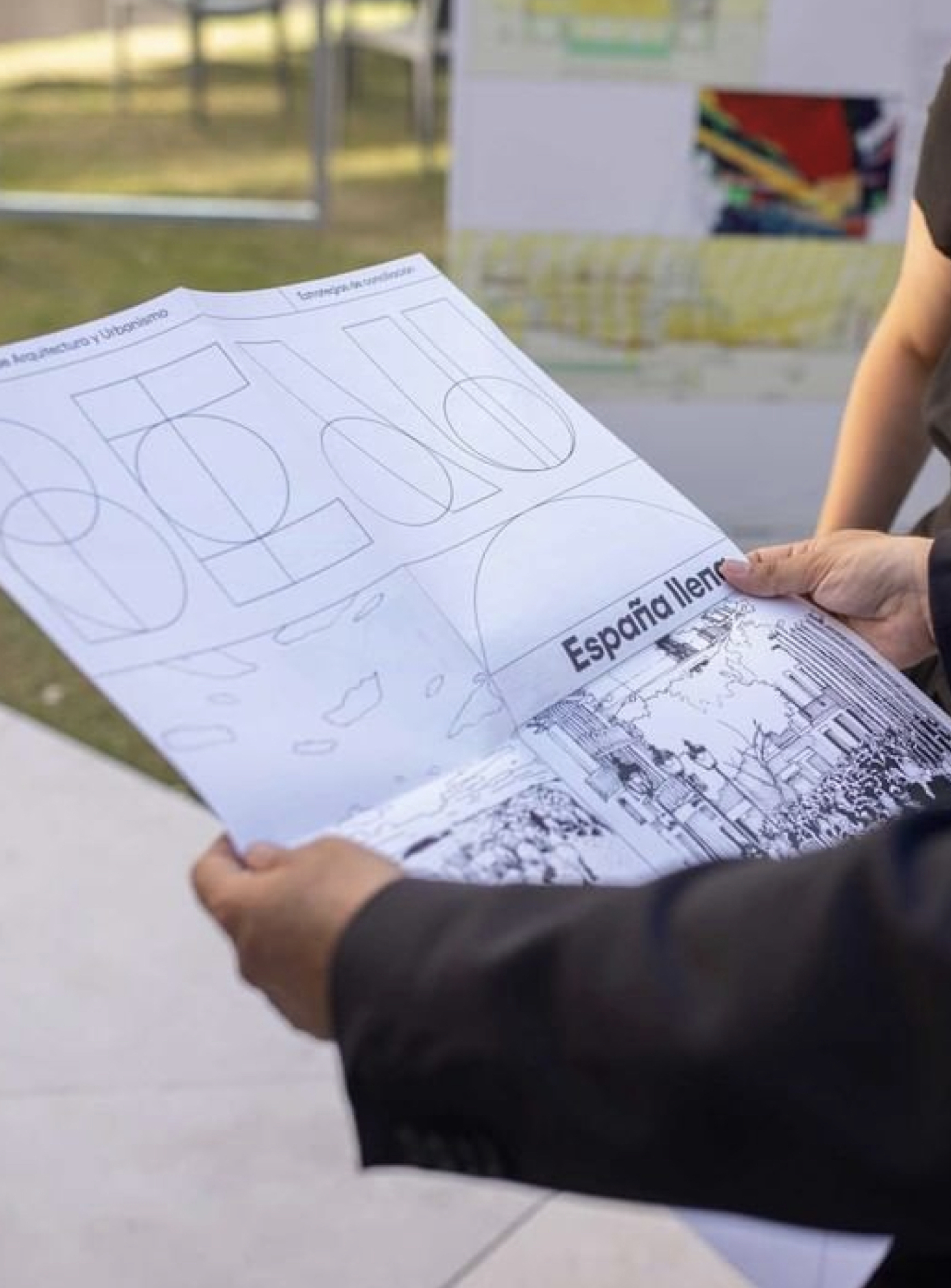 <span><span>Desplegable informatiu de l'esdeveniment en mans d'un dels assistents de la imatge d'un dels cartells de l'exposici&oacute; de XV Biennal Espanyola d'Arquitectura i Urbanisme, Dissenyat per l'estudi esiete de branding i comunicaci&oacute;.</span></span>