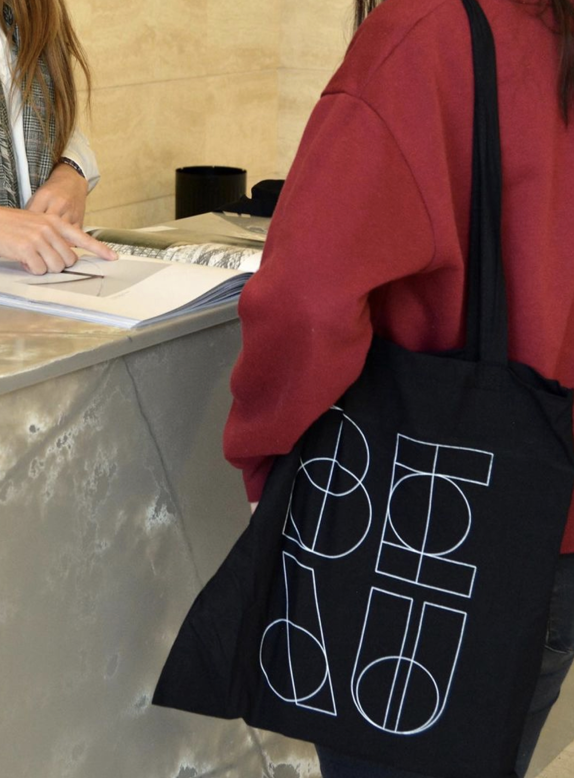 Totebag negra, amb la gr&agrave;fica del XV Biennal Espanyola d'Arquitectura i Urbanisme, on es veu la gent interactuant amb dues s&egrave;ries de cartells en forma de ziga-zaga. Dissenyat per l'estudi esiete de branding i comunicaci&oacute;.