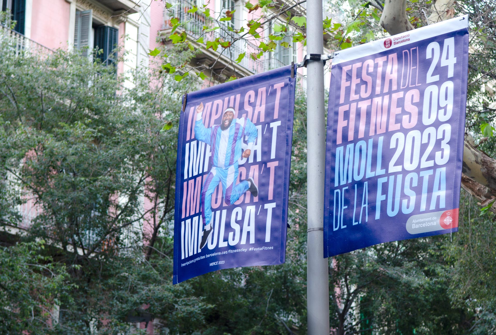 <span><span>Fotografia d'un cartell en un fanal dels carrers de Barcelona per a la campanya de LA FESTA DEL FITNES 2023. Amb el missatge de IMPULSA&rsquo;T amb una fotografia d'un home feli&ccedil;, saltant i amb roba d'esport. Dissenyat per l'estudi esiete de branding i comunicaci&oacute;.</span></span>