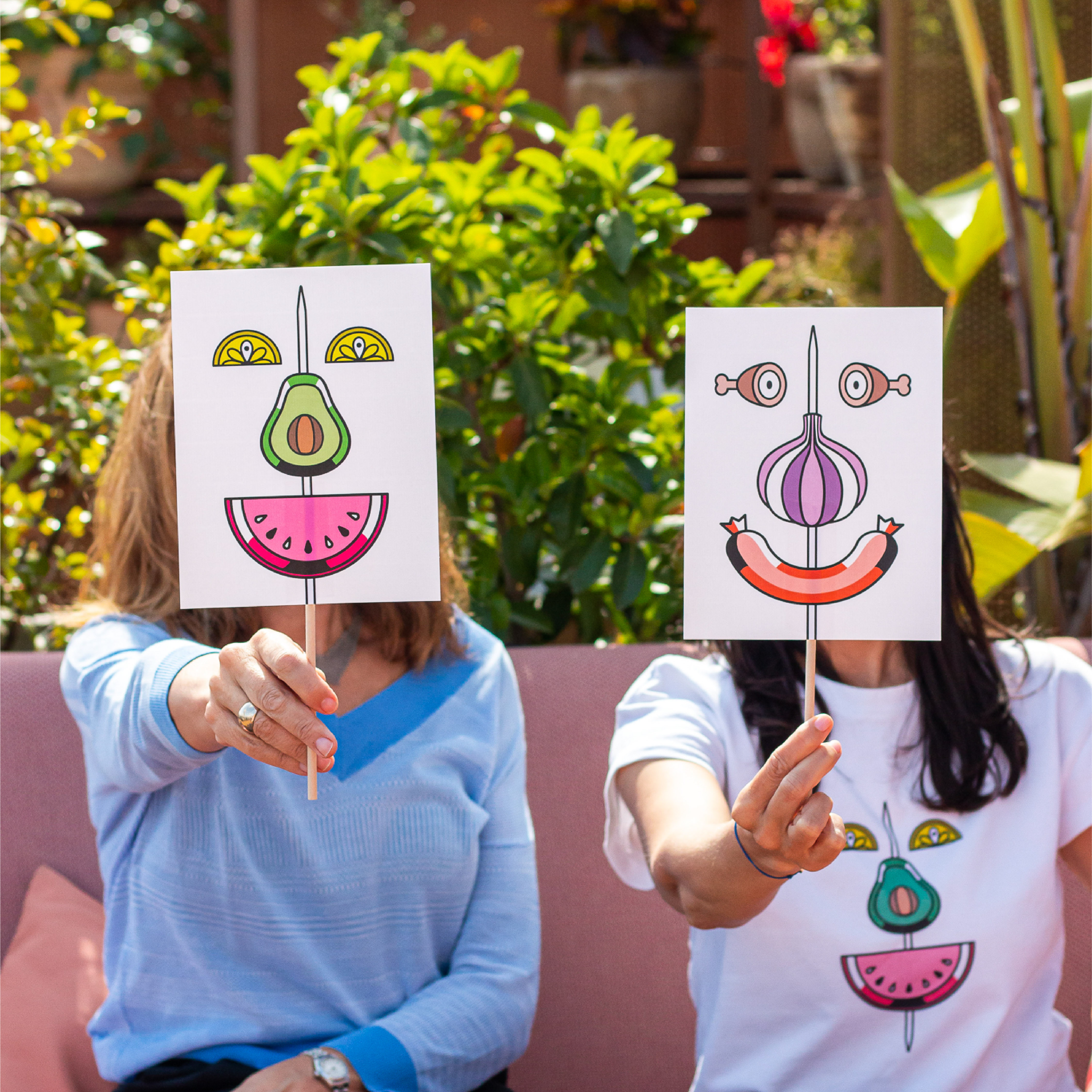 <span><span>Foto de dos chicas, con dos carteles en frente de la cara con la gr&aacute;fica del HOTEL TAPA TOUR 2023, donde aparecen diferentes elementos de tapas formando una cara. Animaci&oacute;n repetitiva donde a partir de un pincho, y elementos que encontramos en platos de tapas, se van formando caras. Dise&ntilde;ado por el estudio esiete de branding y comunicaci&oacute;n.</span></span>